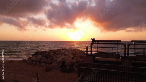 Approaching the beach over rocks and metallic structure in a cloudy sunset