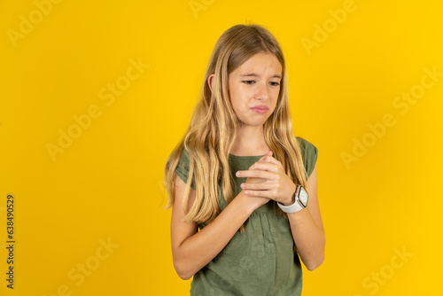 Sad Beautiful caucasian kid girl wearing green dress desperate and depressed with tears on her eyes suffering pain and depression in sadness facial expression and emotion concept