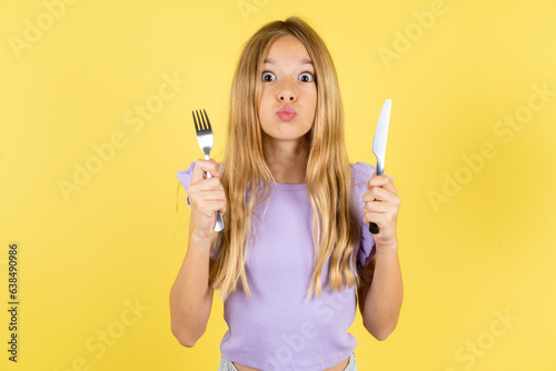 hungry Beautiful caucasian kid girl wearing violet dress holding in hand fork knife want tasty yummy pizza pie