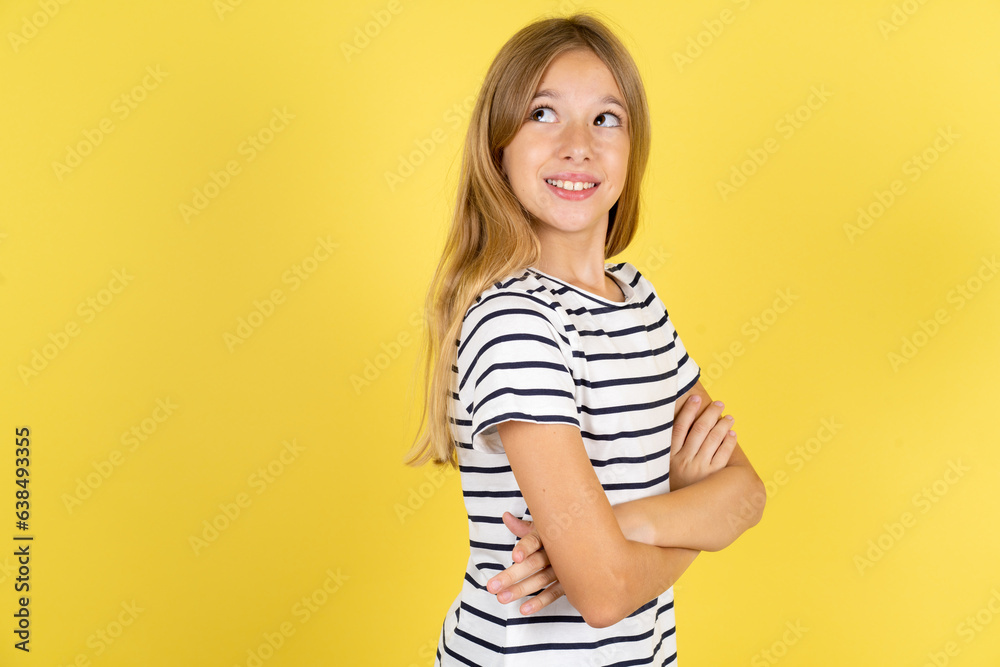 Beautiful caucasian kid girl wearing striped T-shirt arms crossed look empty space billboard Beautiful caucasian kid girl wearing striped T-shirt arms crossed look empty space billboard