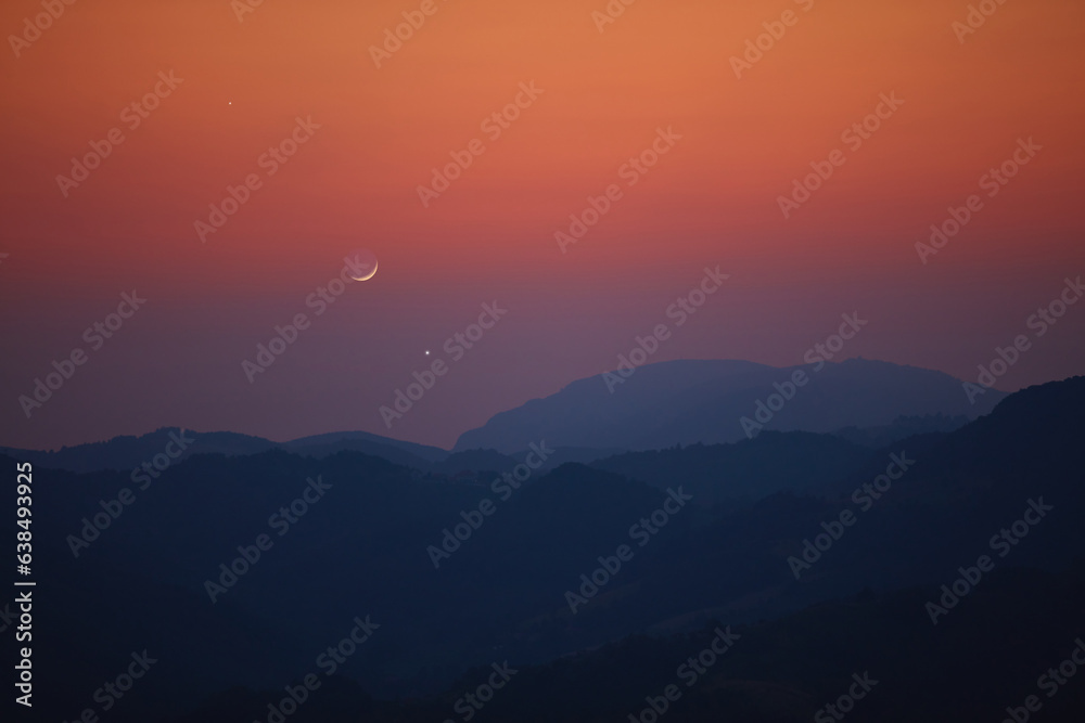 Fototapeta premium Silhouette of a mountain landscape with Milky Way stars, planets and crescent Moon.