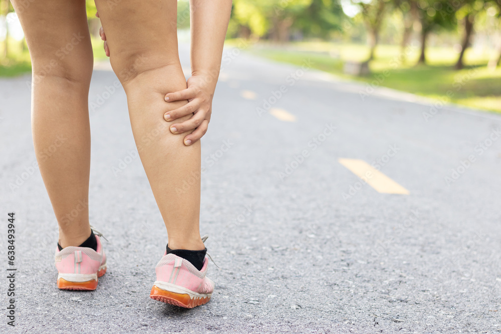 Injury from workout concept. Running sport injury leg pain. Runner woman massaging sore calf muscles during running training outdoor from pain. Female athlete with joint or muscle soreness.