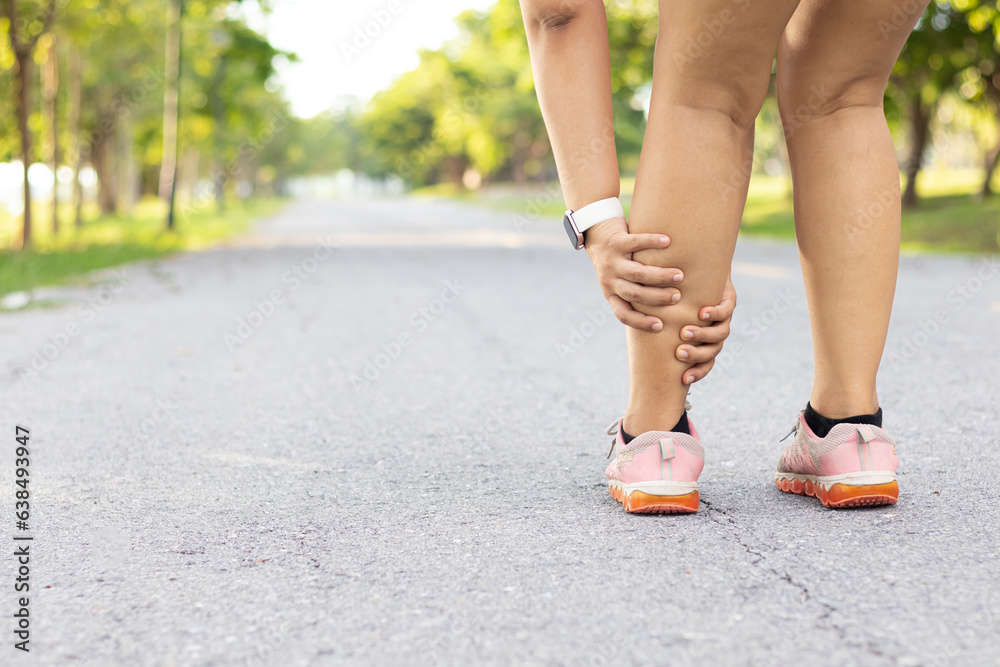 Injury from workout concept. Running sport injury leg pain. Runner woman massaging sore calf muscles during running training outdoor from pain. Female athlete with joint or muscle soreness.
