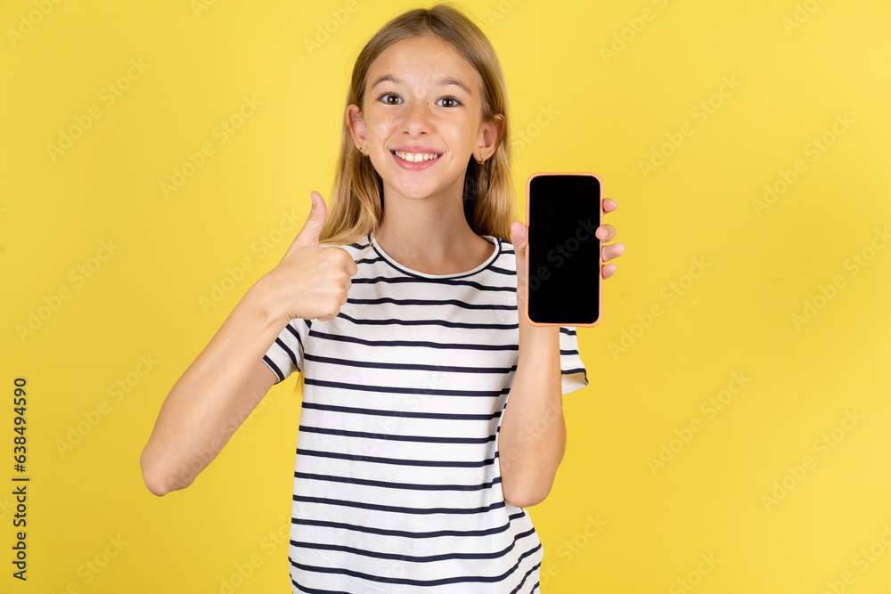 Beautiful caucasian kid girl wearing striped T-shirt Show blank screen smartphone, thumb up recommend new app Beautiful caucasian kid girl wearing striped T-shirt Show blank screen smartphone, thumb up recommend new app