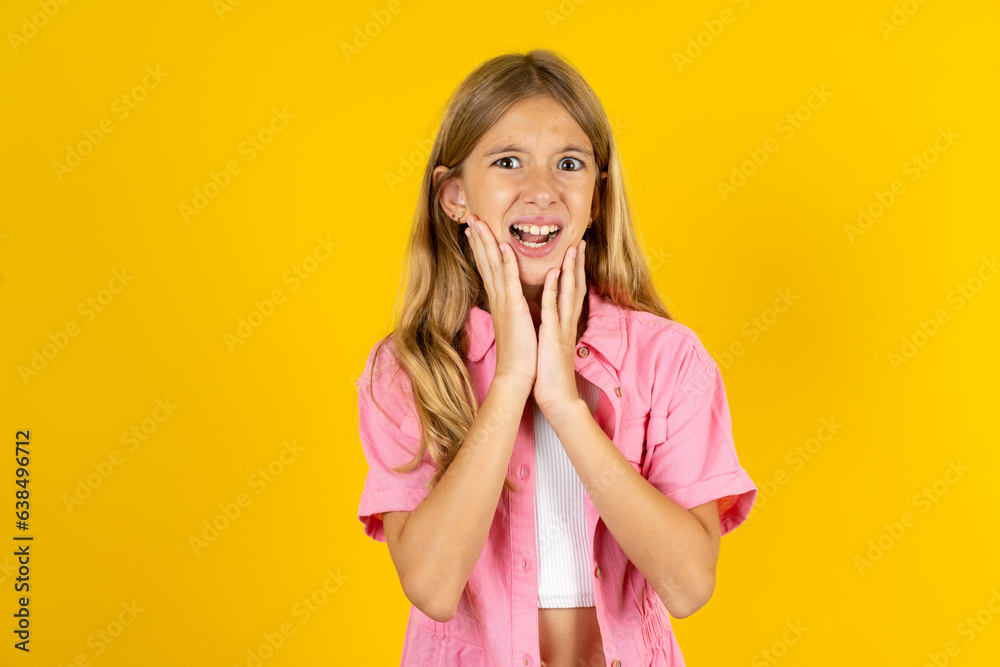Upset Beautiful caucasian kid girl wearing pink shirt touching face with two hands Upset Beautiful caucasian kid girl wearing pink shirt touching face with two hands