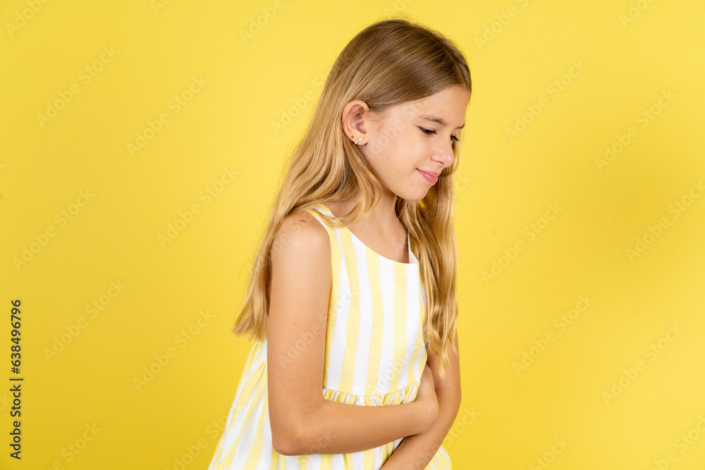 Beautiful caucasian kid girl wearing yellow dress got stomachache Beautiful caucasian kid girl wearing yellow dress got stomachache
