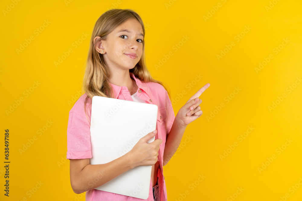 Beautiful caucasian kid girl wearing pink shirt holding laptop showing copy empty space ad Beautiful caucasian kid girl wearing pink shirt holding laptop showing copy empty space ad
