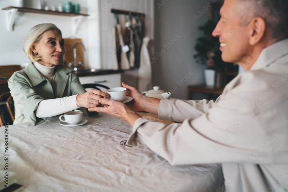 Obraz premium Mature female caring about husband during morning tea at home