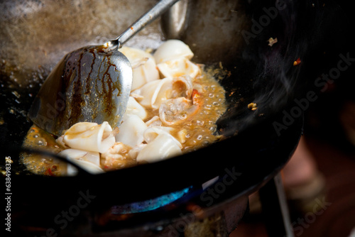 Canvas Print Cooking squid with red curry at a street food stall in Bangkok, Thailand