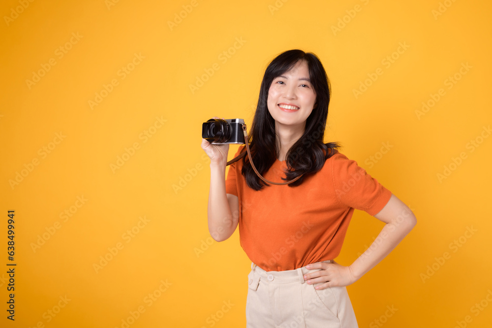 Personable young woman with a camera isolated on yellow background, capturing the essence of a happy vacation traveler.