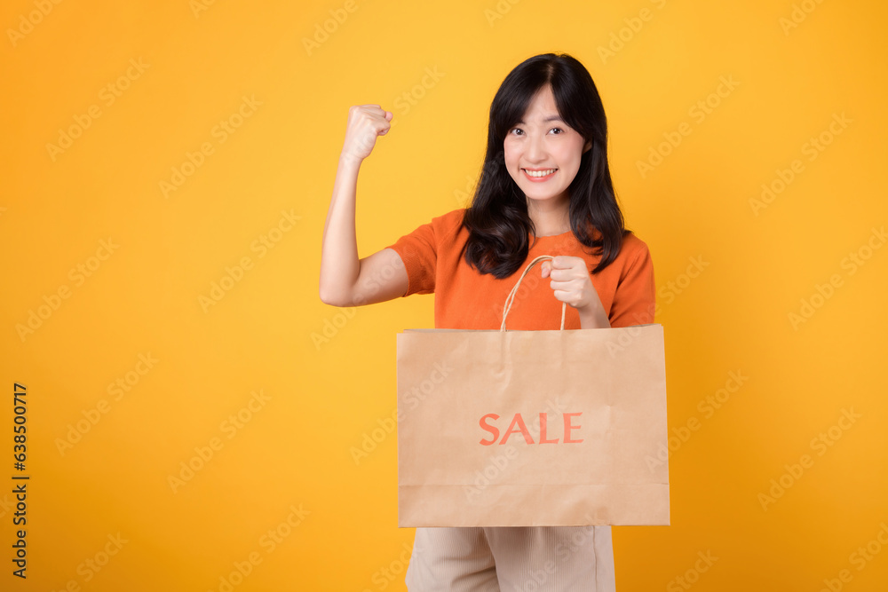 Elevate your shopping journey with love and the best deals in town. Happy young asian woman showcases her purchases, capturing the thrill of both savvy and joyful shopping. on yellow background Elevate your shopping journey with love and the best deals in town. Happy young asian woman showcases her purchases, capturing the thrill of both savvy and joyful shopping. on yellow background