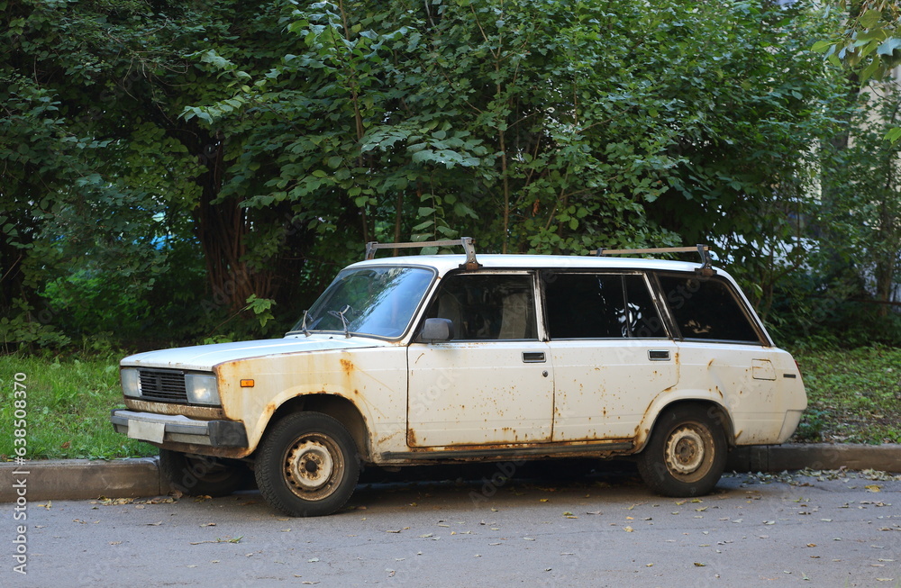 An old white Soviet car stands near the law, Tallinskaya Street, St. Petersburg, Russia, August 23, 2023