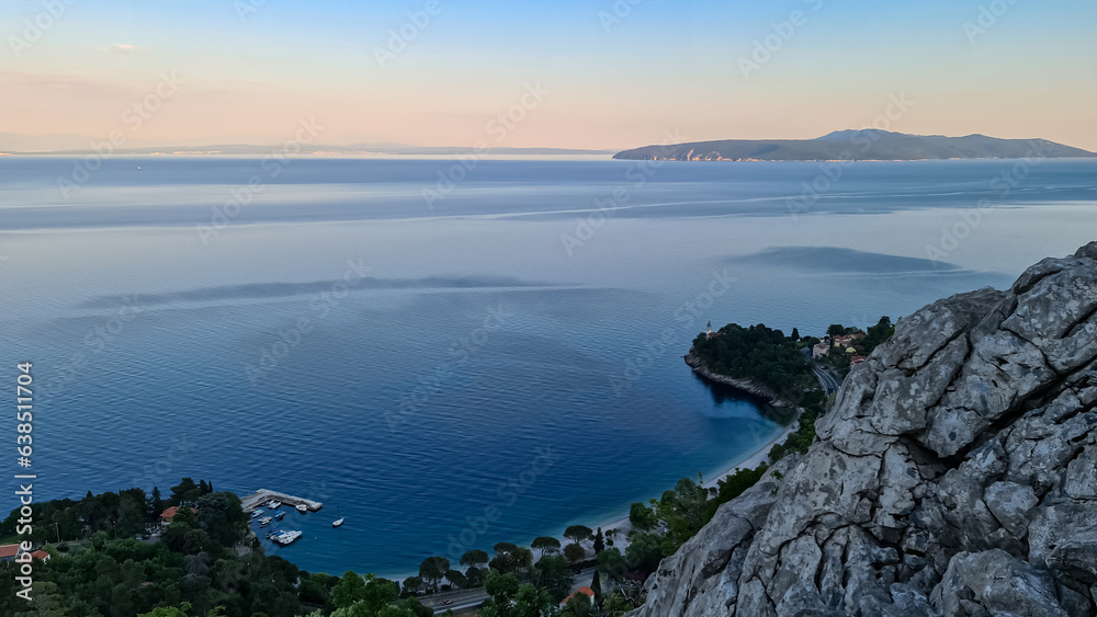 Panoramic view of the shore along Medveja, Croatia. The Mediterranean Sea has turquoise color. Big boulders in the water. An island in the back. Calmness and solitude. Summer holidays. Daybreak