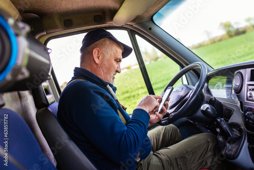 Mature truck driver using mobile phone while driving transport vehicle. © Mediteraneo