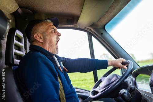 Exhausted truck driver yawning in his van. Tiredness and sleeping concept.