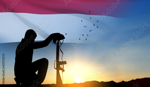 Silhouette of a soldier kneeling down with Yemen flag against the sunset. EPS10 vector