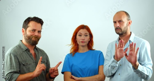 A group of coworkers, a woman and two men, looking at the camera. They are clearly disapproving of something, as they are all shaking their heads and making hand gestures that mean 