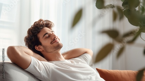 Free Download Satisfied handsome young man relaxing on sofa at home in living room, resting after a hard day work, closed eyes, put hands behind head, smiles happily. Relaxation, self care, enjoy life concept - GFXLoad