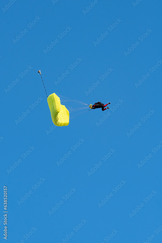 Stunning view of of a skydiver with a yellow parachute and a blue sky in the background