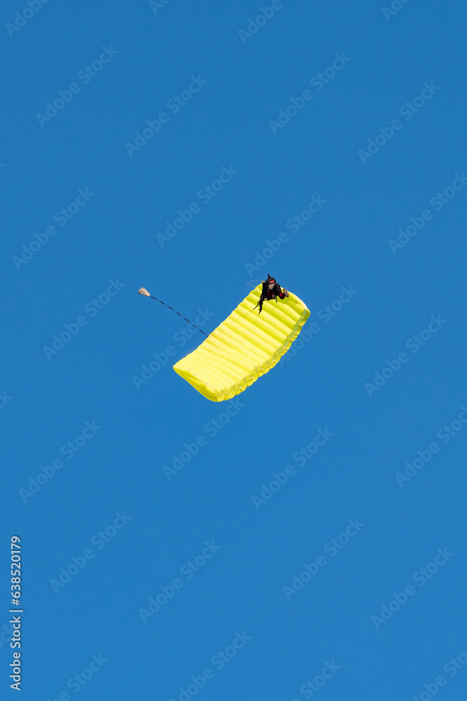 Stunning view of of a skydiver with a yellow parachute and a blue sky in the background
