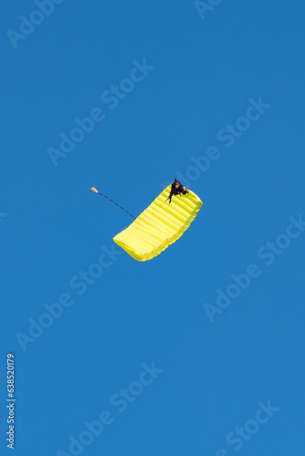 Stunning view of of a skydiver with a yellow parachute and a blue sky in the background
