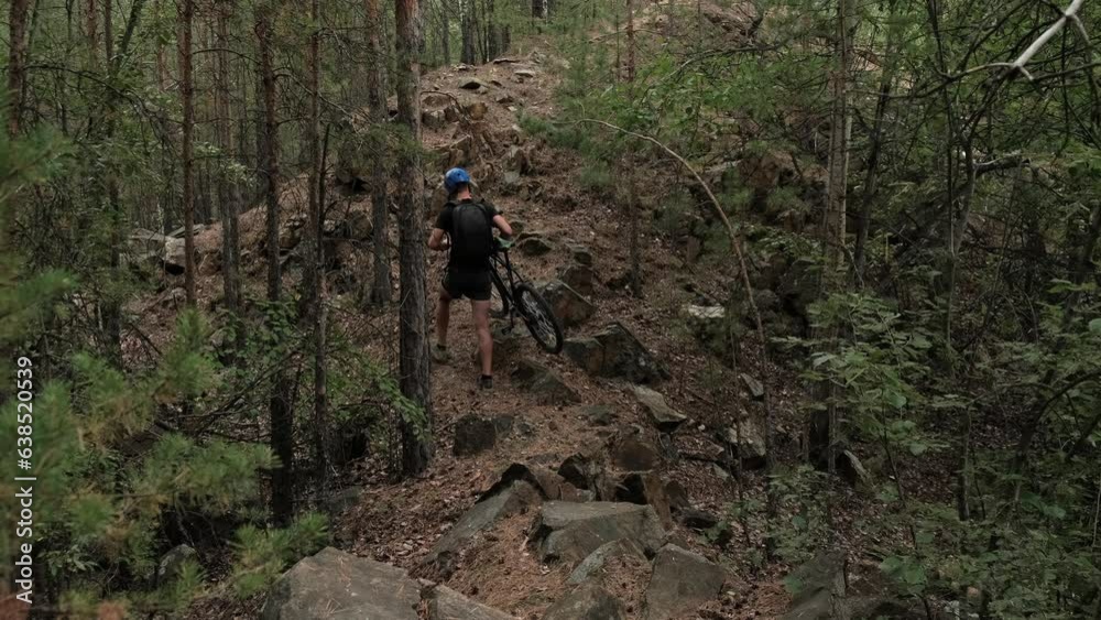 mountain bike.A cyclist in sportswear and a protective helmet lifts a bicycle uphill in a wooded area.Slow motion.Off-road cycling mountain bike.A cyclist in sportswear and a protective helmet lifts a bicycle uphill in a wooded area.Slow motion.Off-road cycling