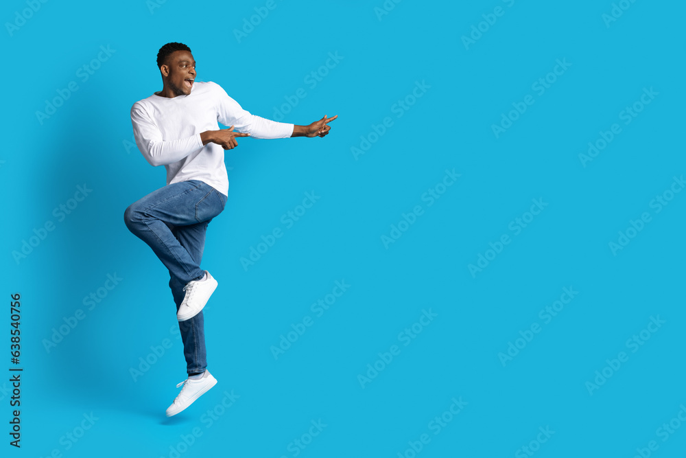 Excited emotional black guy dancing and pointing at copy space Excited emotional black guy dancing and pointing at copy space
