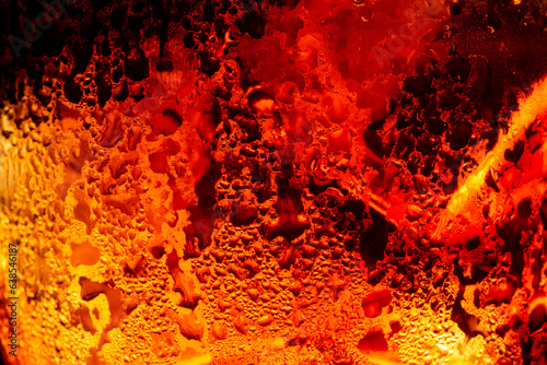 Macro cola drink background,Close up view of ice cubes in dark cola background. Surface of sweet summer cold drink with foam and macro bubbles on glass wall. Fizzing or float to the top of the surface