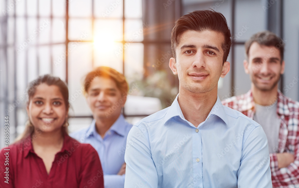 A group of business people dressed in casual clothes pose proudly in the office.