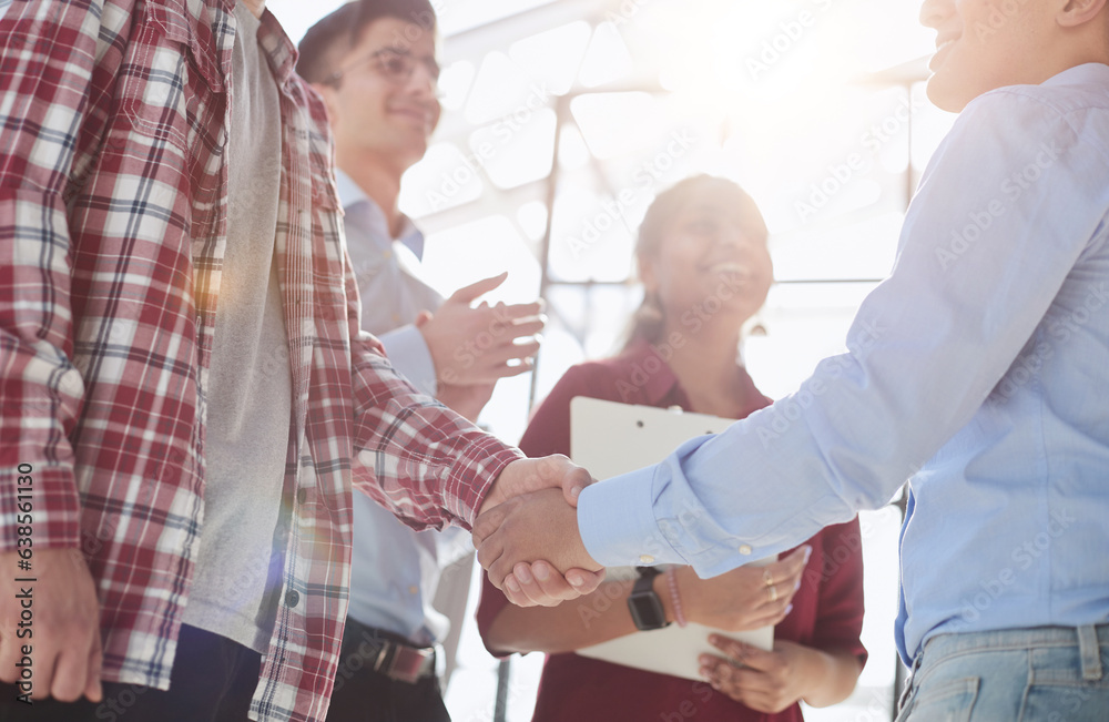 Obraz premium Young startup in casual clothes shaking hands in a modern office space by the window.