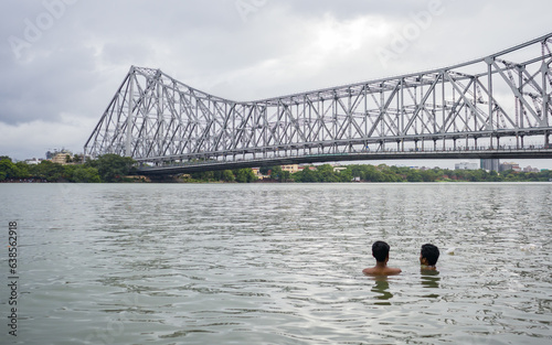 two boys bathing together in the hooghly river water in kolkata. Majestic howrah bridge in the background. photo symbolizes acceptance of homosexuality  or gay relationship or friendship. photo