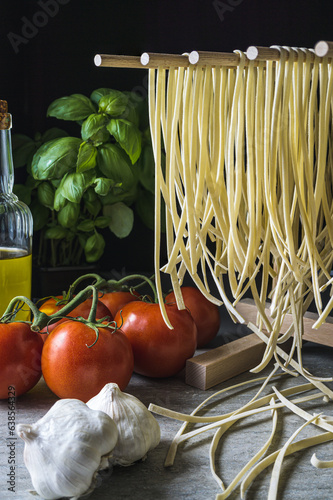 Fresh linguine pasta drying on a wooden rack.