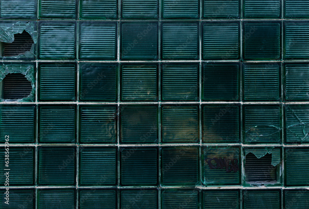 Damaged glass block window at an infrastructure facility. Dark background. The concept of stealth.