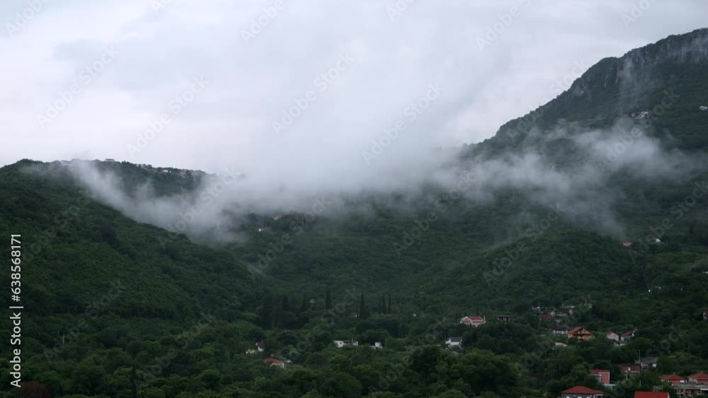 Small village in high mountains overgrown with trees and covered with low rain clouds. Small village in high mountains overgrown with trees and covered with low rain clouds.