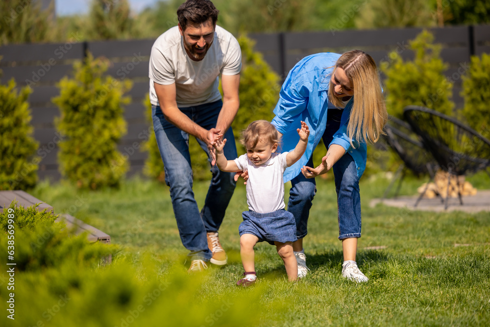 Fototapeta premium Young cute family playing with their kid in the park