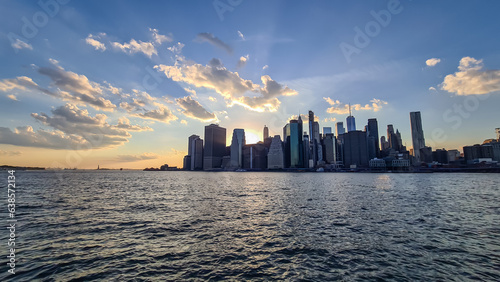 Manhattan cityscape at dusk with iconic skyscrapers reflecting on the Hudson River. Great density of skyscrapers, some of them are reflecting the sunbeams of setting sun. Vibrant city. © Chris