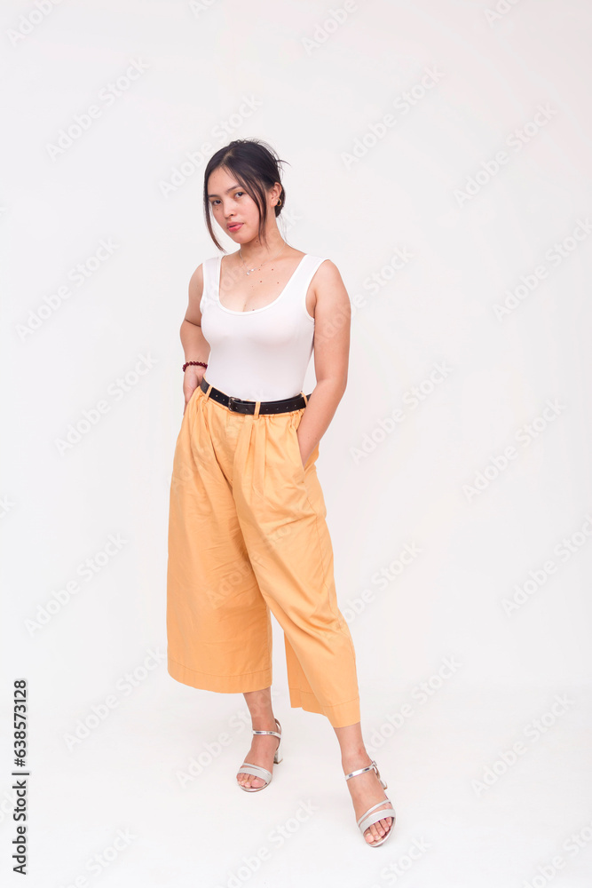 A stoic and intense young Asian woman staring fiercely ahead with hands in pockets. Isolated on a white background. A stoic and intense young Asian woman staring fiercely ahead with hands in pockets. Isolated on a white background.
