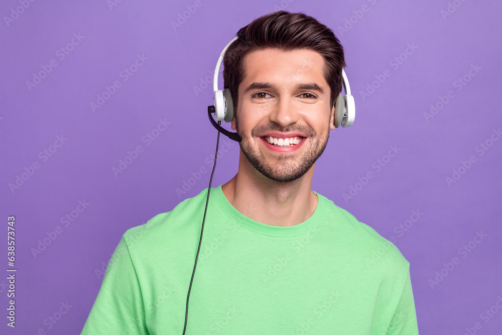 Photo of brunet man wear green stylish t-shirt listen professional gadget headset microphone call center isolated on violet color background Photo of brunet man wear green stylish t-shirt listen professional gadget headset microphone call center isolated on violet color background