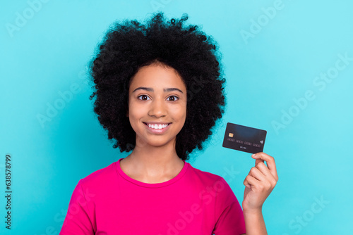 Photo of toothy beaming girl with afro chevelure wear pink t-shirt fingers demonstrate credit card isolated on blue color background