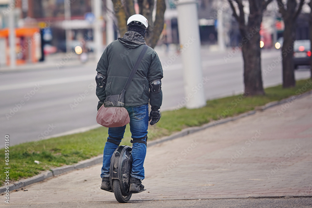 Man in protective gear riding electric unicycle, monocycle or mono