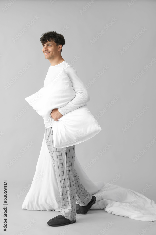 Handsome happy man with soft blanket and pillow on grey background Handsome happy man with soft blanket and pillow on grey background