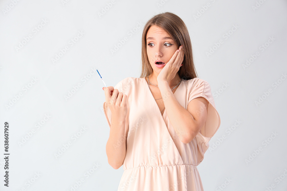 Shocked beautiful young woman with pregnancy test on grey background Shocked beautiful young woman with pregnancy test on grey background