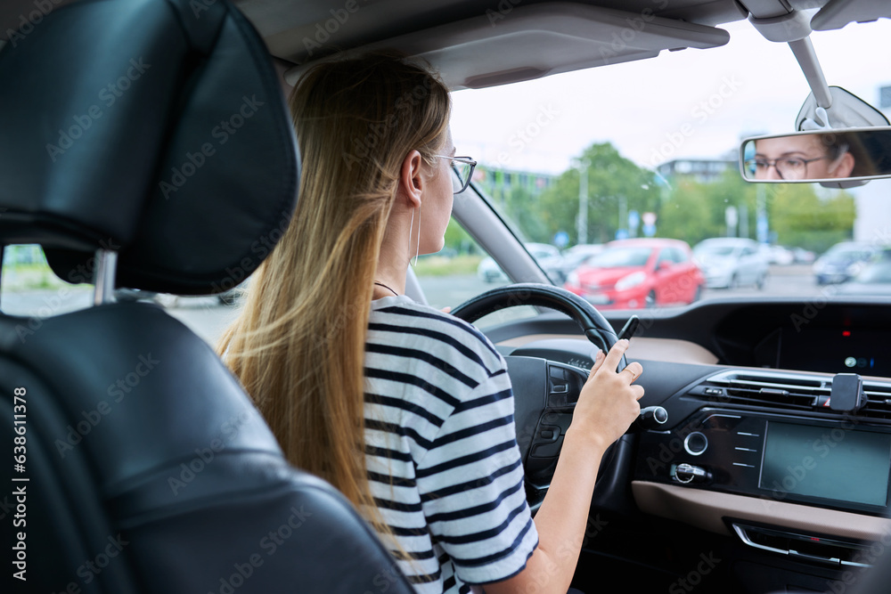 Teenage girl driver in glasses sitting behind wheel of car