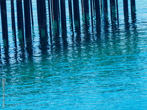 Pier pilings casting reflections on blé seawater, Eureka California