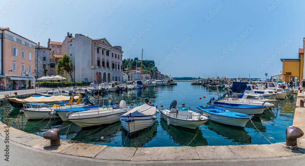 A view across boats moored in the inner harbour towards the town of Piran, Slovenia in summertime