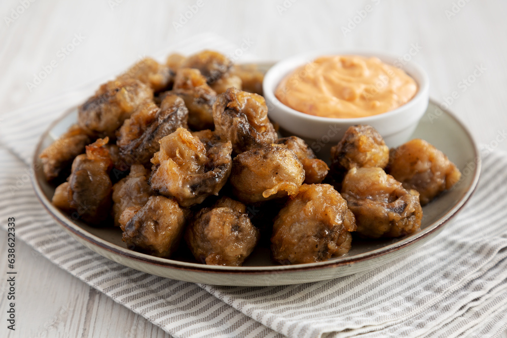 Homemade Crispy Deep Fried Mushrooms with Spicy Mayo on a Plate on a white wooden background, side view. Close-up. Homemade Crispy Deep Fried Mushrooms with Spicy Mayo on a Plate on a white wooden background, side view. Close-up.