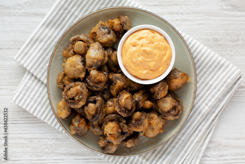 Homemade Crispy Deep Fried Mushrooms with Spicy Mayo on a Plate on a white wooden background, top view.