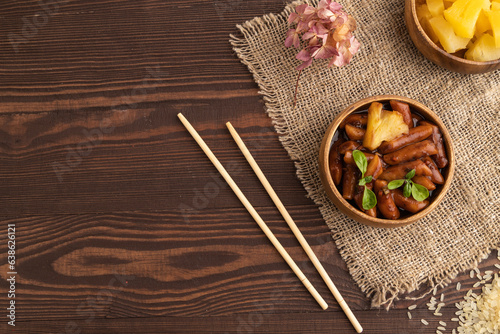 Tteokbokki or Topokki, fried rice cake stick, on brown wooden, top view, copy space photo