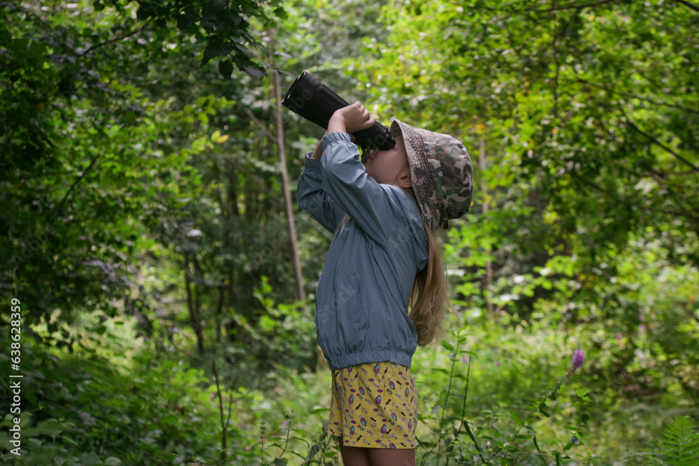 Cute little girl exploring nature looking through binoculars. Child playing outdoors. Kids travel, adventure and bird watching concept.
Cute little girl exploring nature looking through binoculars. Child playing outdoors. Kids travel, adventure and bird watching concept.