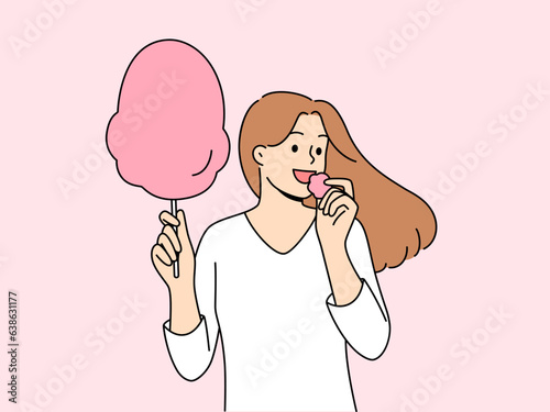 Woman eats cotton candy, enjoying airy sugar dessert while walking in park or at fair. Carefree girl holding cotton candy and experiencing positive emotions from lack of important things to do